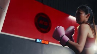 Spor salonunda Asyalı kadın boks antrenmanını yakından çek. Öfkeli kız kum torbasıyla boks yapar. Spor Dayanıklılık.