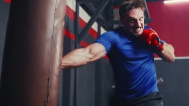 Beyaz adamın spor salonunda boks antrenmanını yakından çek. Öfkeli adam kum torbasıyla boks yapar. Spor Dayanıklılık.
