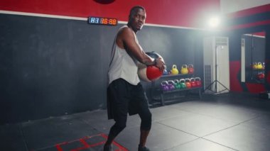 Sallanan ağırlık topuyla spor yapan siyahi bir sporcunun tam karesi..