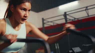 Asya 'lı bir kadının spor salonunda hava bisikleti sürerken ve kameraya gülümserken yakın çekimi..