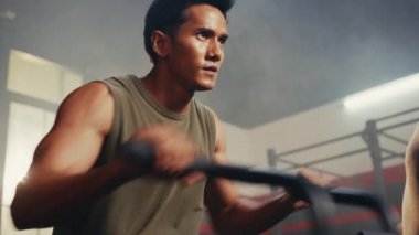 Asian men using exercise machines in the gym with concentration and determination for achievement.