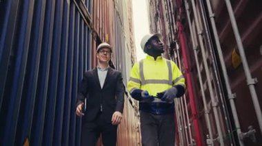 Foreman ve müfettişin düşük seviye açısı, limanda lojistik ihracat ve ithalatın kalite kontrolü için konteyner kutusunu kontrol ediyor..
