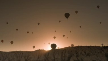 Low angle of hot air balloons flying over deserted sandstone valley in cloudless sky in Cappadocia. High quality 4k footage