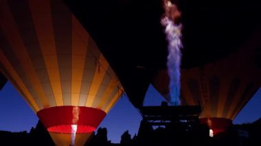 Close up shot of hot air balloons with propane burner big fire flames against cloudless clear dark blue sky of Cappadocia in Turkey at dawn. High quality 4k footage.