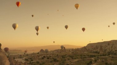 Low angle of hot air balloons flying over famous Love valley at dawn in cloudless sky in Cappadocia. High quality 4k footage