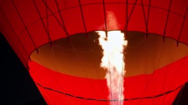 Slow motion close up of big fire flame burner ignition and glowing hot air balloon in darkness in Cappadocia. High quality 4k footage