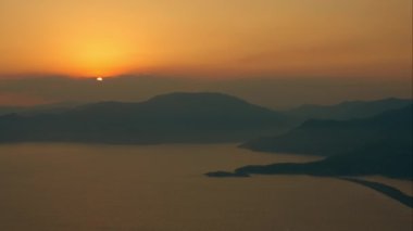 Aerial view of spectacular sunset scenery with mountains and hills silhouettes surrounding calm sea lagoon above Turtle beach near Dalyan in Turkey
