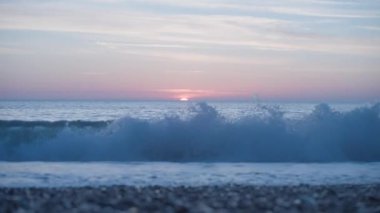 Beautiful soothing sea sunset with moderate waves crash on pebble shingle beach. High quality 4k footage