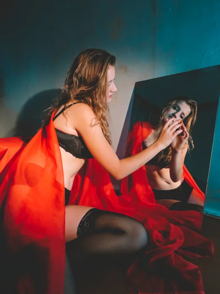 鏡の前に赤いベールと黒い下着を着た若い美しいブロンドの女性 女性の体の美学と美しさ 化粧品 ボディケア — ストック写真