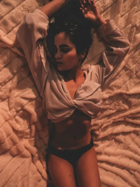 셔츠와 팬티를 체구의 여자가 가벼운 침대위에 — 스톡 사진
