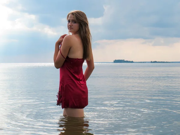 헐렁하고 몸매의 매력적 드레스를 채더운 여름날얕은 해변에서 일광욕 바다에서 수영하는 — 스톡 사진