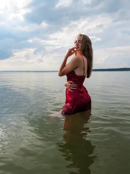 헐렁하고 몸매의 매력적 드레스를 채더운 여름날얕은 해변에서 일광욕 바다에서 수영하는 — 스톡 사진