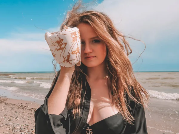 비키니를 머리를 조개껍데기를 셔츠를 여성은 해변에서의 여름날 파도를 배경으로 휴일의 — 스톡 사진