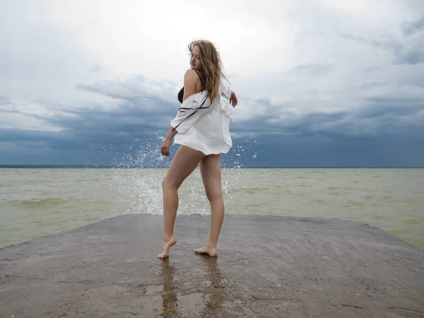비키니를 수영복을 셔츠를 바람에 나부끼는 금발의 머리를 어두운 폭풍우를 배경으로 — 스톡 사진