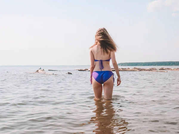 年轻的金发女子 夏天穿着紫色比基尼在海滩上有着纤细的运动身材 美丽而美观的女性身体 海滩假日 积极的生活方式 户外运动 晒黑的皮肤 — 图库照片