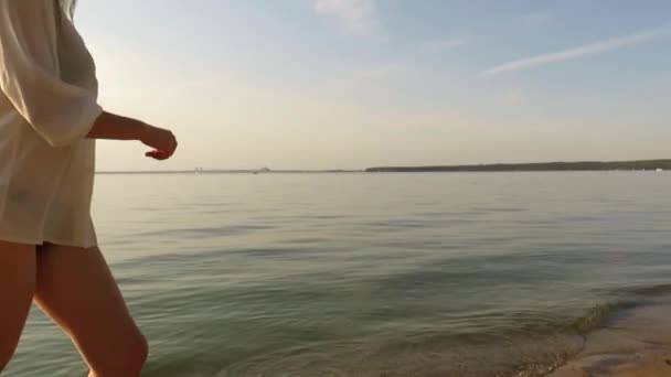 美丽的年轻女子 身材苗条 身穿比基尼泳衣 穿着丝质衬衫 夕阳西下沿着沙滩奔跑 是户外活动的概念 与周围世界的团结 海滩季节 — 图库视频影像