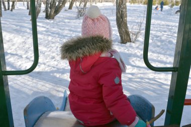 Çocuk kış ormanında kaydırağında oynuyor.