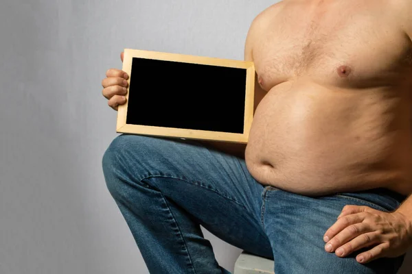 Overweight Shirtless Caucasian Man Sitting Holding Blackboard — стоковое фото