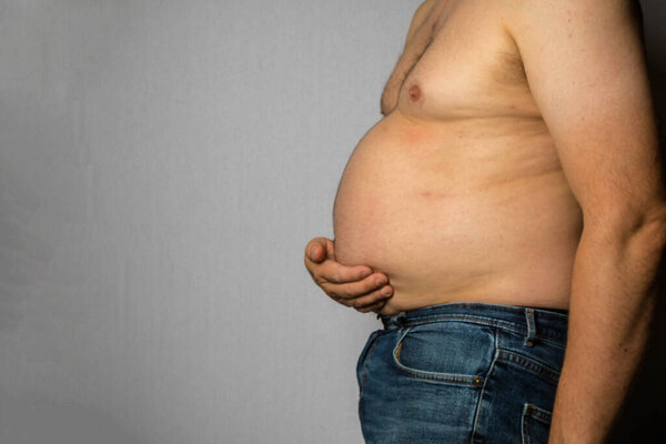 An Overweight Shirtless Caucasian Man Standing Sideways Holding His Fat