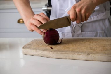 Evcil bir mutfakta merhem doğrayan genç bir çocuk.