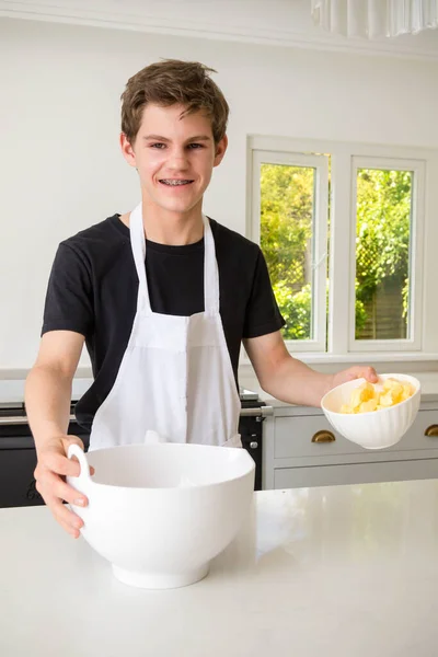 Mladý Chlapec Domácí Kuchyni Přidává Máslo Mísy — Stock fotografie