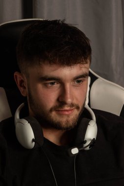 Bir üniversite erkek öğrencisi kulaklık takıp video oyunu oynuyor.