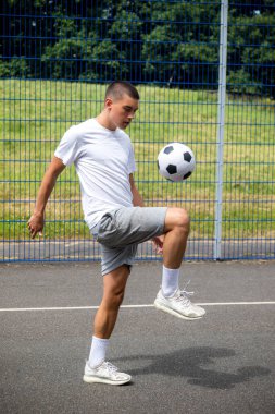 Halka açık bir parkta futbol oynayan 19 yaşında bir genç çocuk.