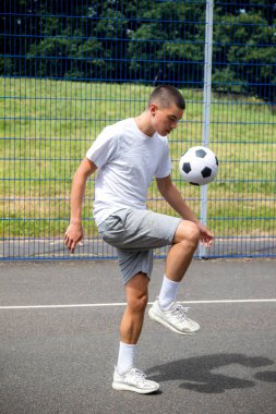 Halka açık bir parkta futbol oynayan 19 yaşında bir genç çocuk.