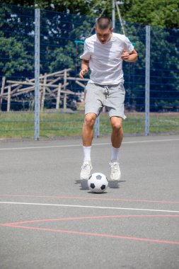 Halka açık bir parkta futbol oynayan 19 yaşında bir genç çocuk.