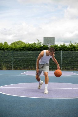 A Nineteen Year Old Teenage Boy Playing Basketball in A Public Park