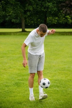 Halka açık bir parkta futbol oynayan 19 yaşında bir genç çocuk.