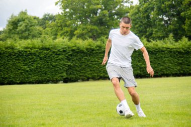 Halka açık bir parkta futbol oynayan 19 yaşında bir genç çocuk.