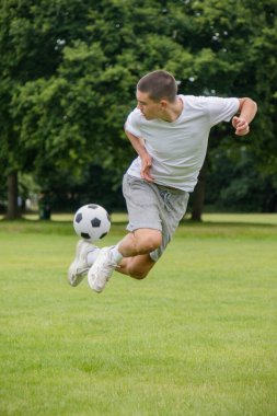 Halka açık bir parkta futbol oynayan 19 yaşında bir genç çocuk.
