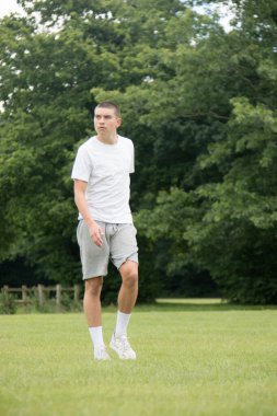Halka açık bir parkta futbol oynayan 19 yaşında bir genç çocuk.
