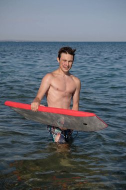 A 17 Year Old Teenage Boy In The Sea With A Body Board