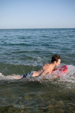 A 17 Year Old Teenage Boy In The Sea With A Body Board