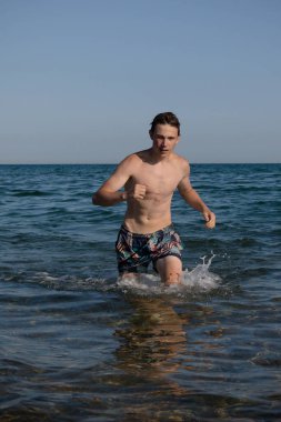 A 17 Year Old Teenage Boy Walking Out Of The Sea