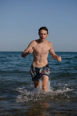 A 17 Year Old Teenage Boy Walking Out Of The Sea