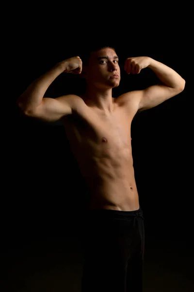 Shirtloser Jähriger Teenager Der Seine Arme Vor Schwarzem Hintergrund Beugt — Stockfoto