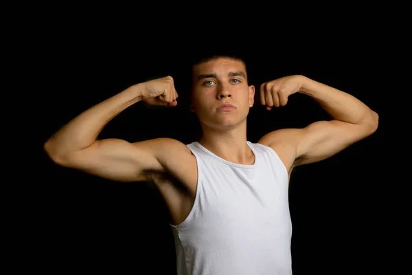 19 year old teenage boy wearing a tank top flexing his arm muscles