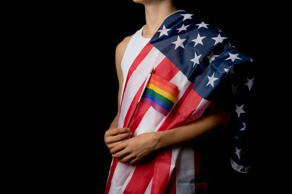 A portrait of a nineteen year old teen boy on a black background with an American Flag and white board and Pride Flags