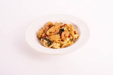 Beyaz tabakta baharatlı deniz ürünleri makarnası.