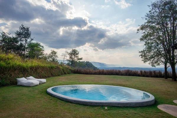 The swimming pool in the garden and the mountain background.