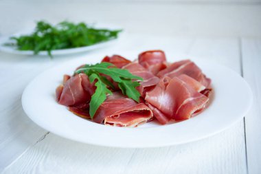 Beyaz arkaplanda jamonlu plaka, yakın plan.