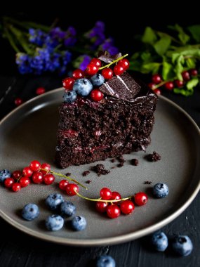 Böğürtlenli çikolatalı pasta ve siyah arka planda yaban mersini.