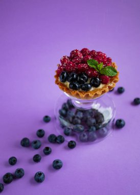 Taze yaban mersinli tatlı, ahududu ve mor arkaplanda nane şekeri.