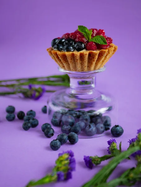 Taze yaban mersinli tatlı, ahududu ve mor arkaplanda nane şekeri.