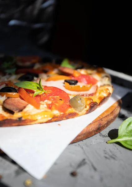 Göğüs eti, sosis, domates ve zeytinli pizza.