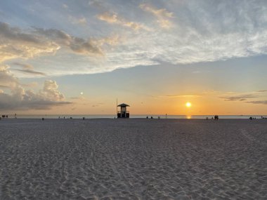 Kumsalda sıcak, rahatlatıcı bir akşam, güzel bir gün batımı, sakin bir okyanus.