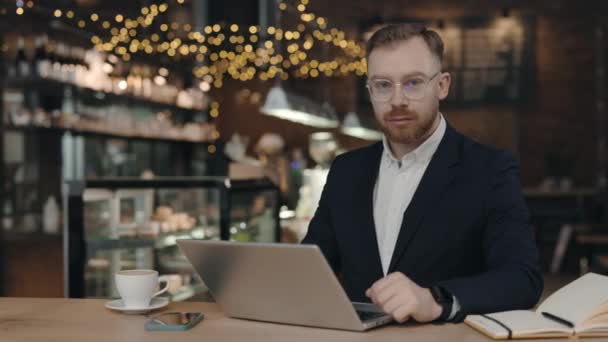 Портрет бізнесмена, який дивиться на камеру під час роботи в кафетерії — стокове відео